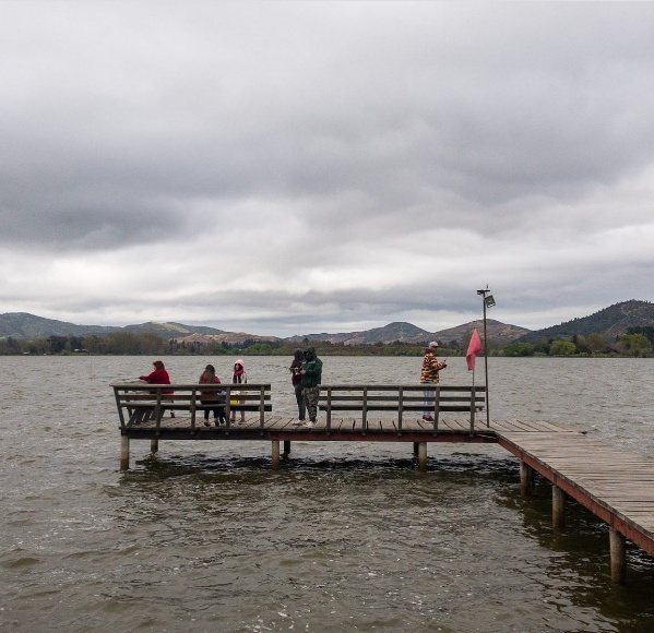 Muelle de madera del camping sobre el lago, con campistas pescando